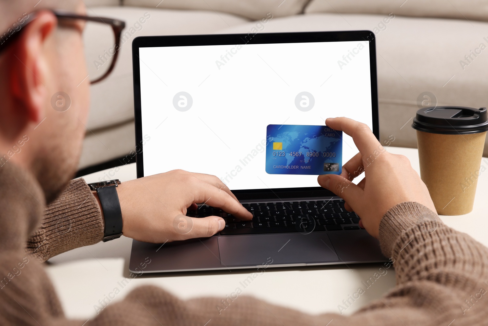 Photo of Man with credit card using laptop for online shopping at white table indoors, closeup