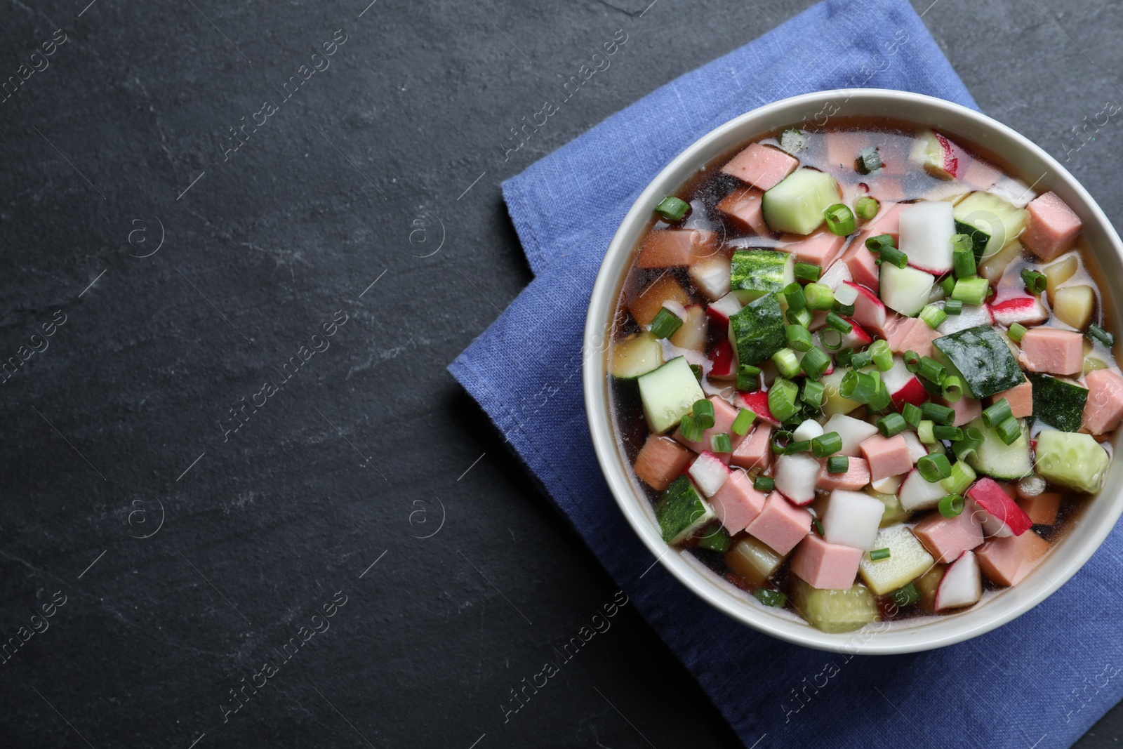 Photo of Delicious cold okroshka with kvass on black table, top view and space for text. Traditional Russian summer soup