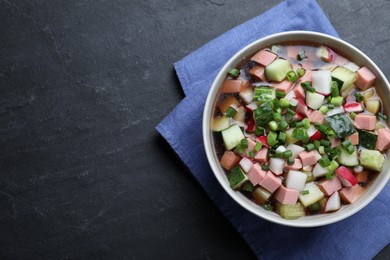 Photo of Delicious cold okroshka with kvass on black table, top view and space for text. Traditional Russian summer soup