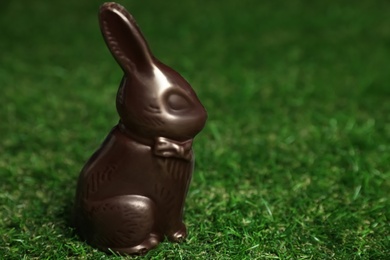 Photo of Chocolate bunny on green grass, space for text. Easter celebration