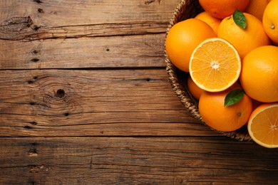 Many ripe oranges and green leaves on wooden table, top view. Space for text