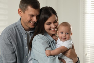 Happy family. Couple with their cute baby near window indoors