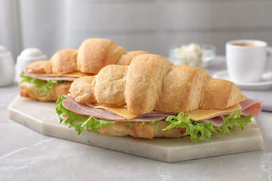 Photo of Tasty croissant sandwiches with ham on grey kitchen table