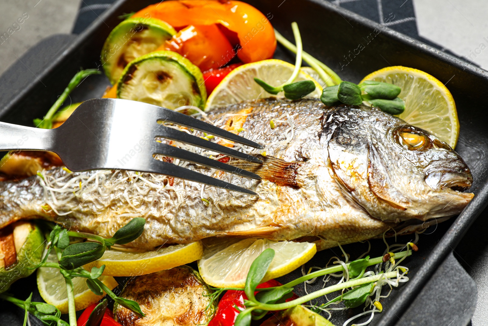 Photo of Delicious roasted fish and vegetables in pan, closeup