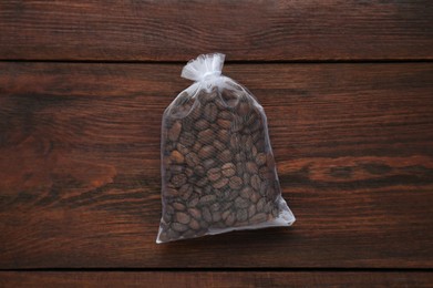Photo of Scented sachet with coffee beans on wooden table, top view