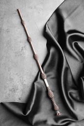 Magic wand and dark cloth on light grey background, top view