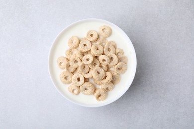 Breakfast cereal. Tasty corn rings with milk in bowl on grey table, top view