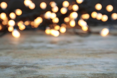 Photo of Wooden table and blurred Christmas lights on background