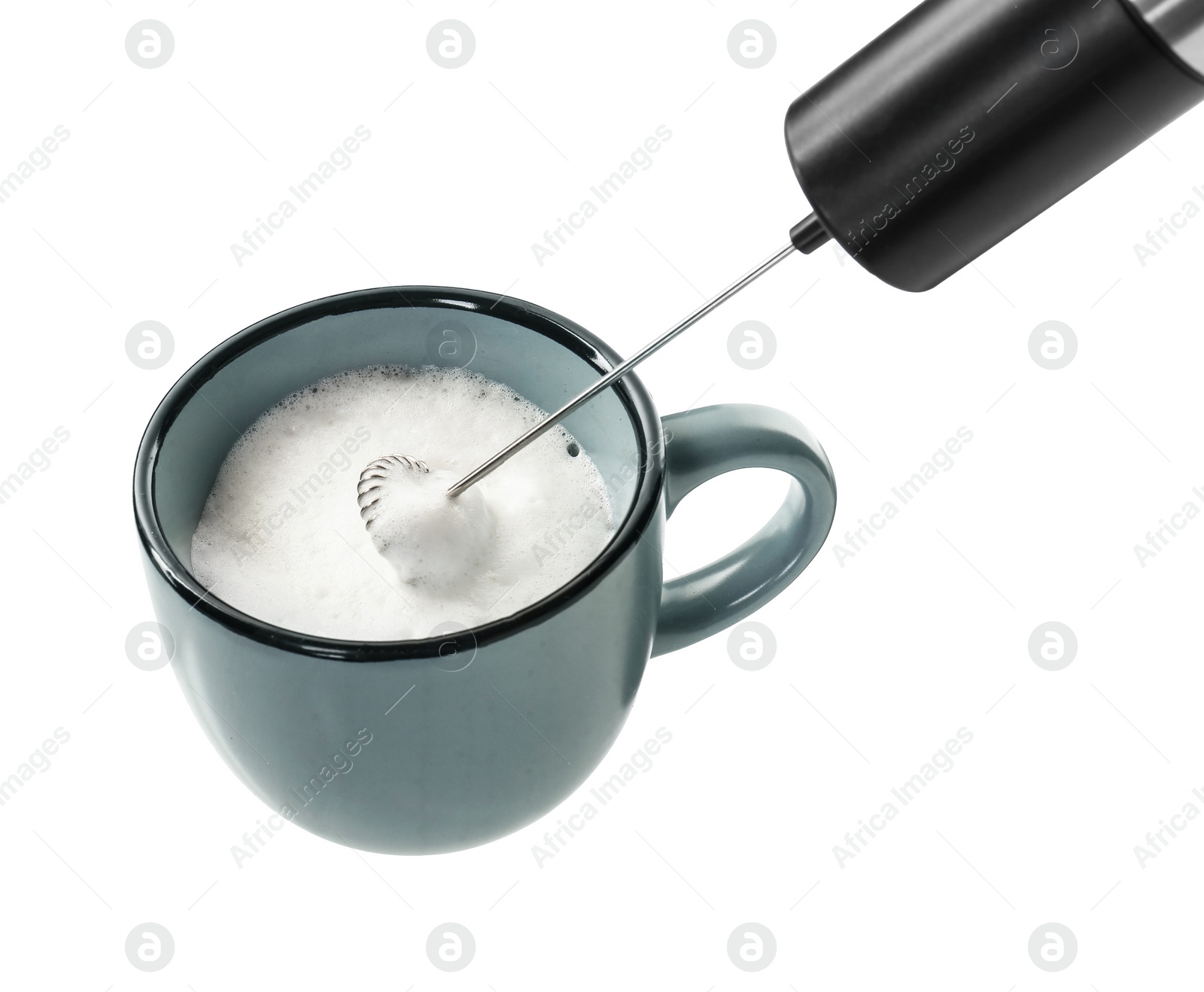 Photo of Whisking milk in cup with mini mixer (frother wand) isolated on white, closeup