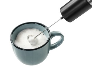 Whisking milk in cup with mini mixer (frother wand) isolated on white, closeup