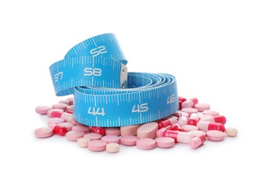 Weight loss pills and measuring tape on white background