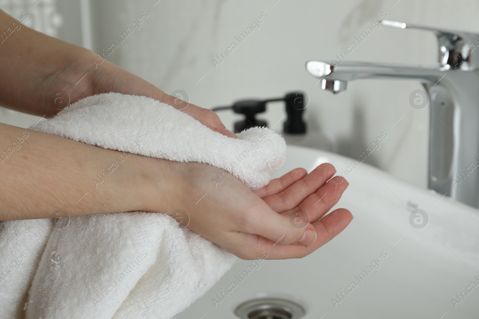 Photo of Woman wiping hands with towel in bathroom, closeup