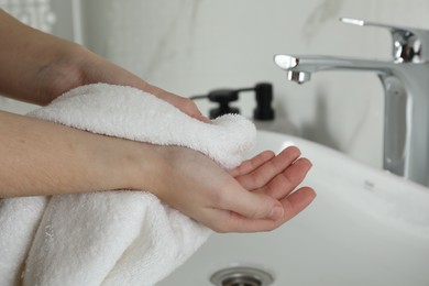 Photo of Woman wiping hands with towel in bathroom, closeup