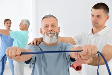 Professional physiotherapist working with senior patient in rehabilitation center