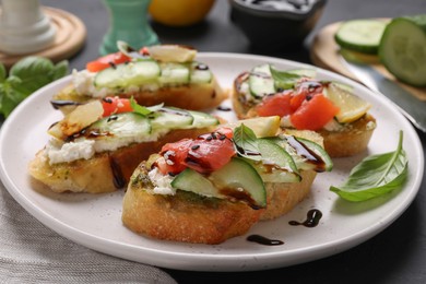 Photo of Delicious bruschettas with balsamic vinegar and toppings on table, closeup
