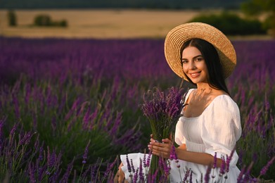 Beautiful young woman with bouquet sitting in lavender field