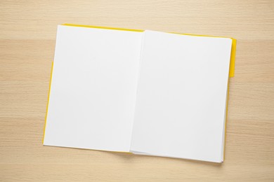 Yellow file with blank sheets of paper on wooden table, top view. Space for design