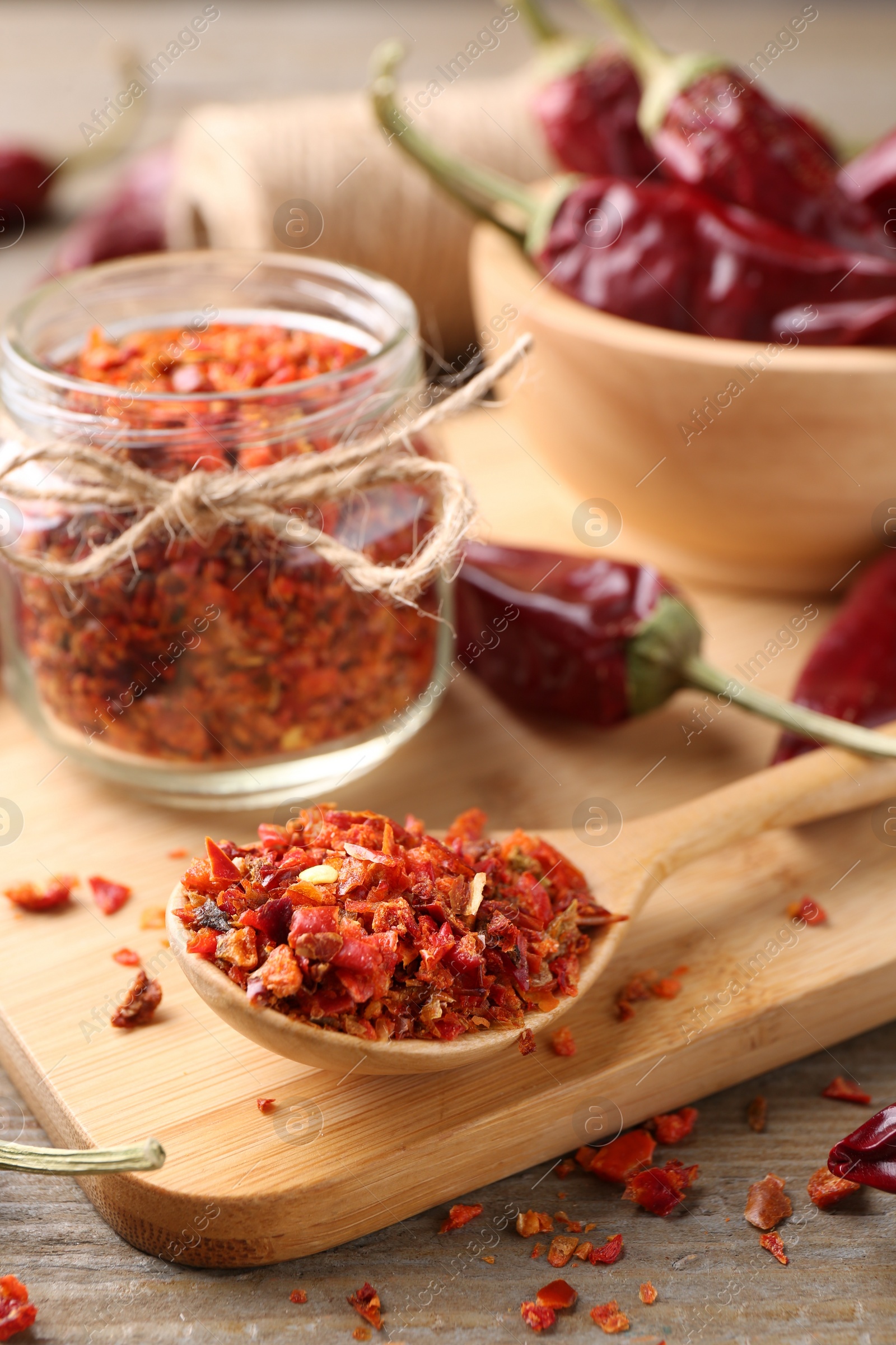 Photo of Chili pepper flakes and pods on wooden table