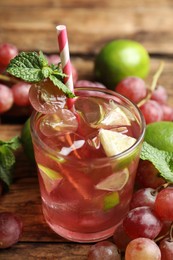 Photo of Soda water with grapes, ice, lime and mint on wooden table. Refreshing drink