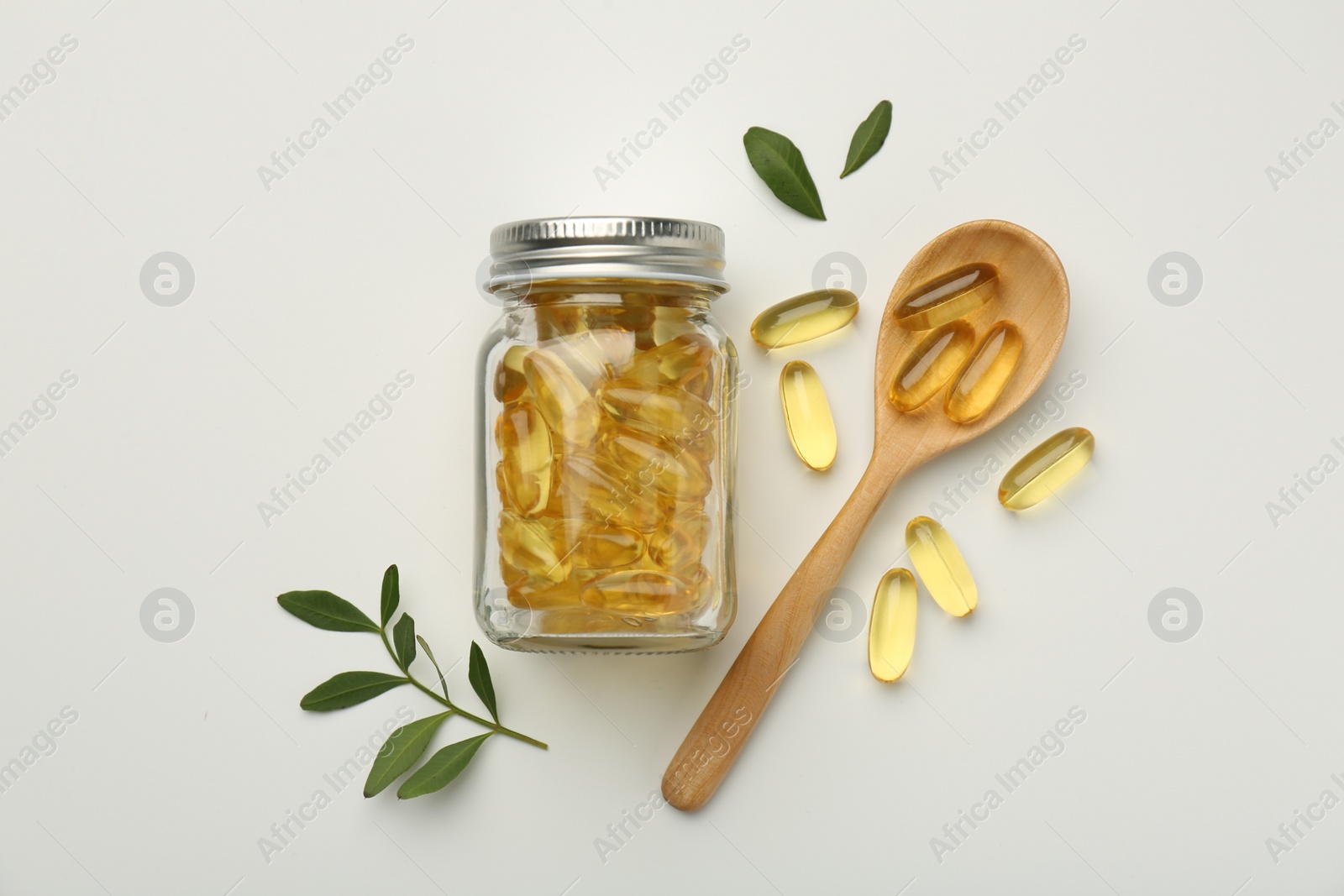 Photo of Bottle, vitamin capsules, spoon and leaves on white background, flat lay