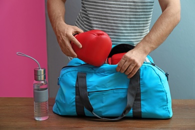 Photo of Young man packing sports bag on table