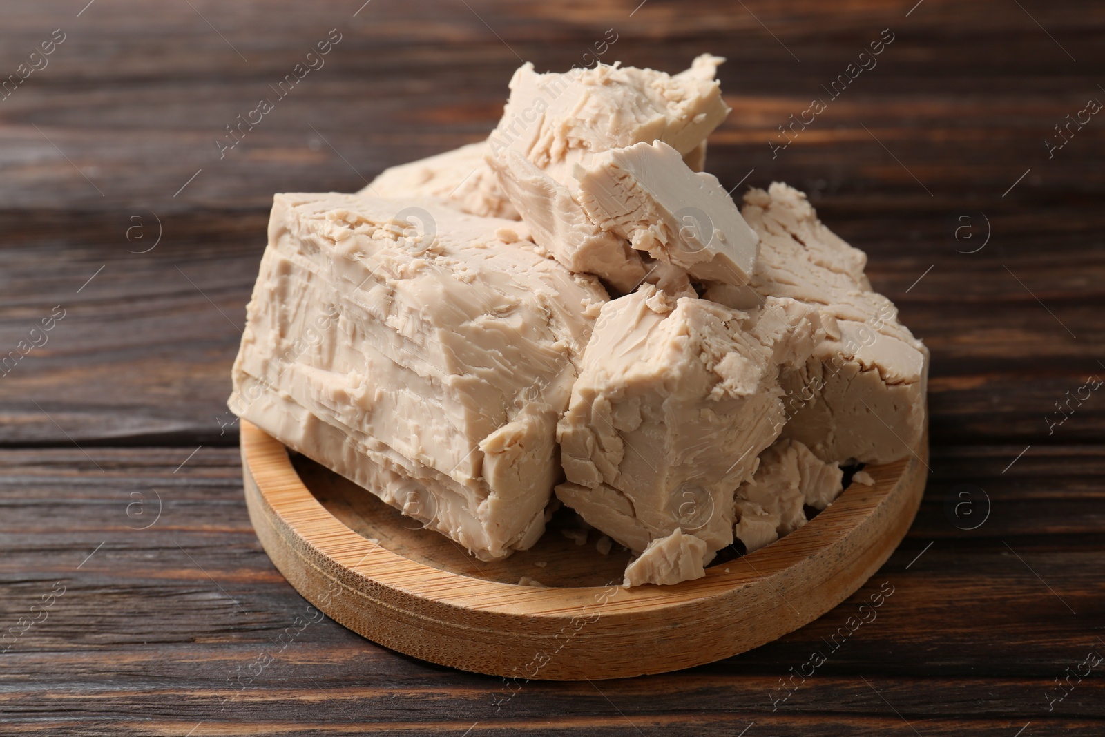 Photo of Closeup view of compressed yeast on wooden table