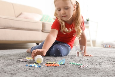 Little child with many different pills on floor at home. Danger of medicament intoxication