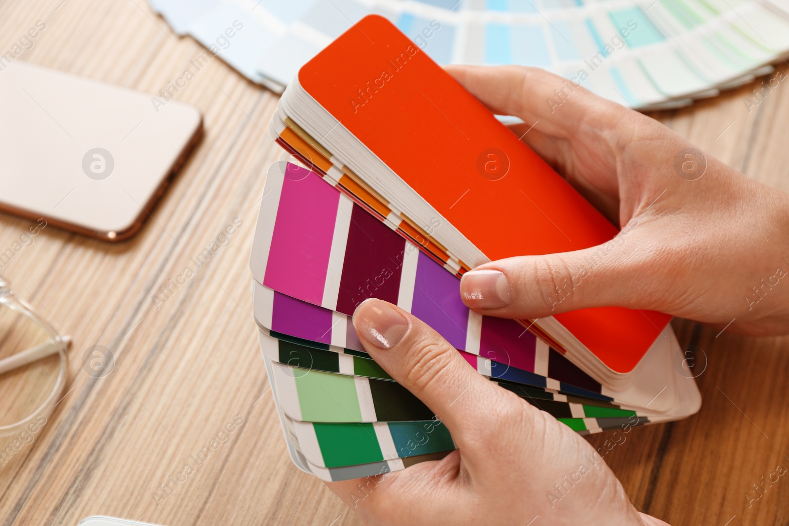 Photo of Woman with palette samples at wooden table, closeup