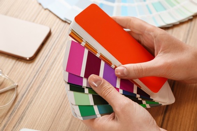 Photo of Woman with palette samples at wooden table, closeup