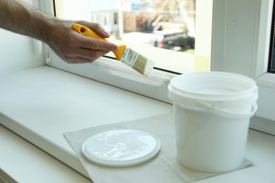 Man painting window frame at home, closeup