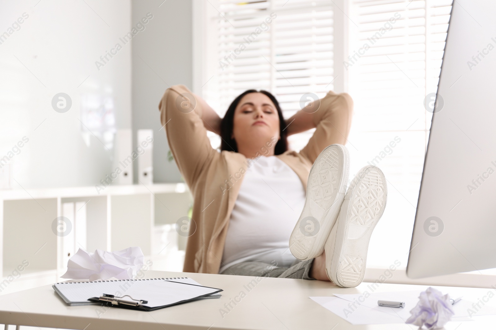 Photo of Lazy overweight worker with feet on desk in office