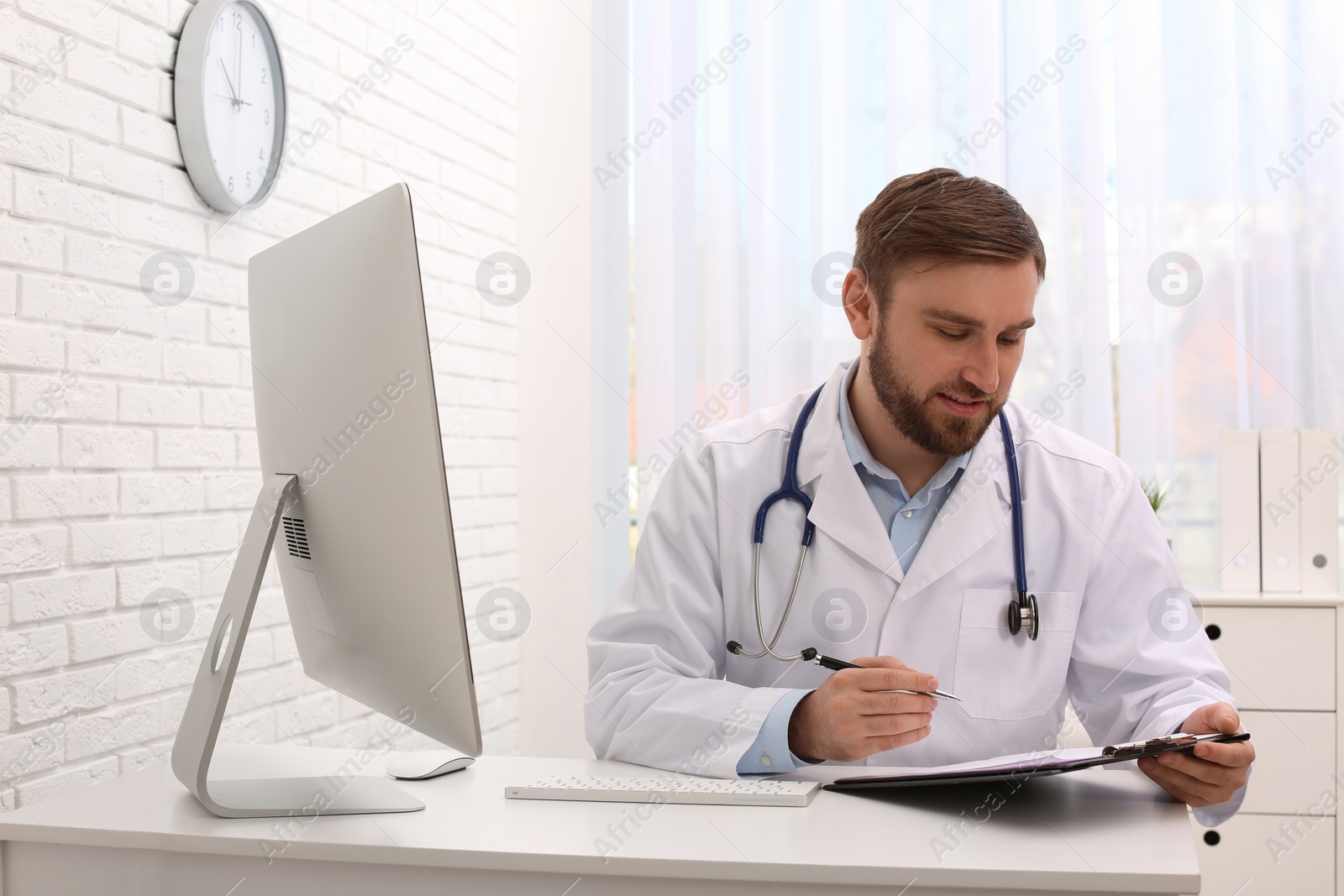 Photo of Pediatrician with clipboard working at table in clinic