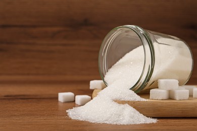 Overturned jar and white sugar on wooden table, space for text