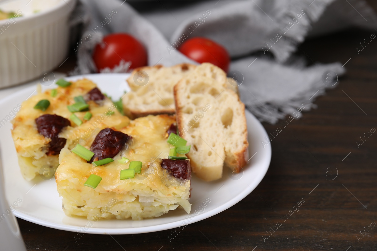 Photo of Tasty sausage casserole with green onion and bread on wooden table, closeup