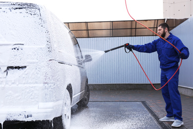 Photo of Worker covering automobile with foam at car wash
