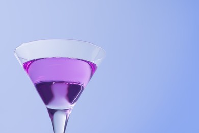 Photo of Fresh cocktail in martini glass on light blue background, closeup. Space for text