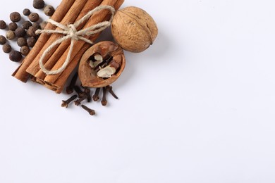 Different spices and nuts on white table, flat lay. Space for text