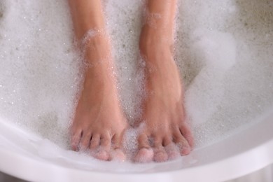 Photo of Woman taking bath in tub with foam, closeup