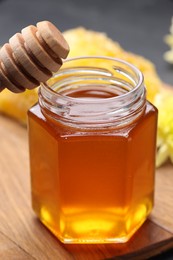 Photo of Sweet honey in jar and dipper on table, closeup