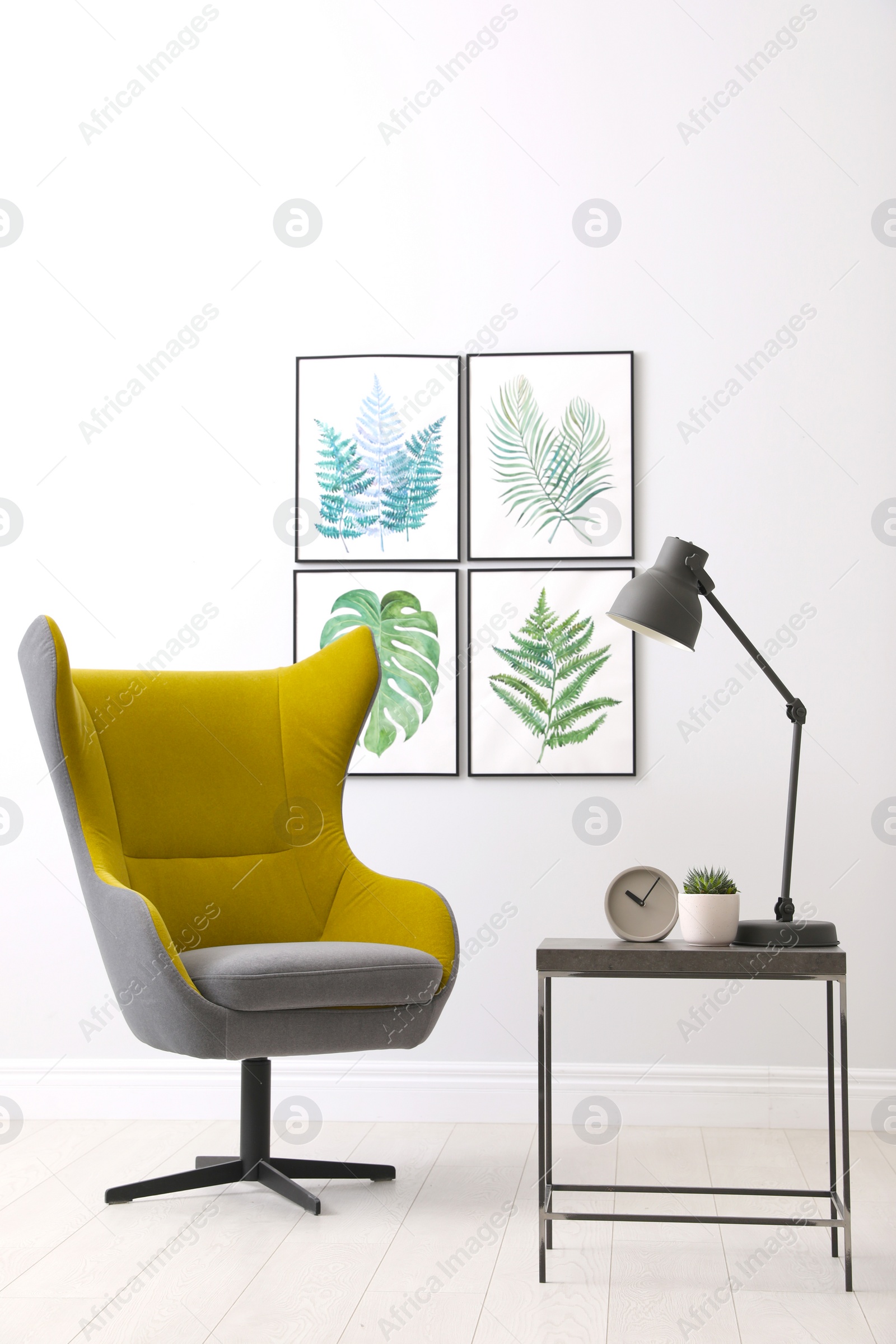 Photo of Stylish room interior with comfortable armchair and paintings of tropical leaves