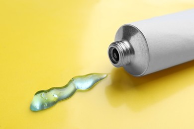 Photo of Open white tube with ointment on yellow background, closeup