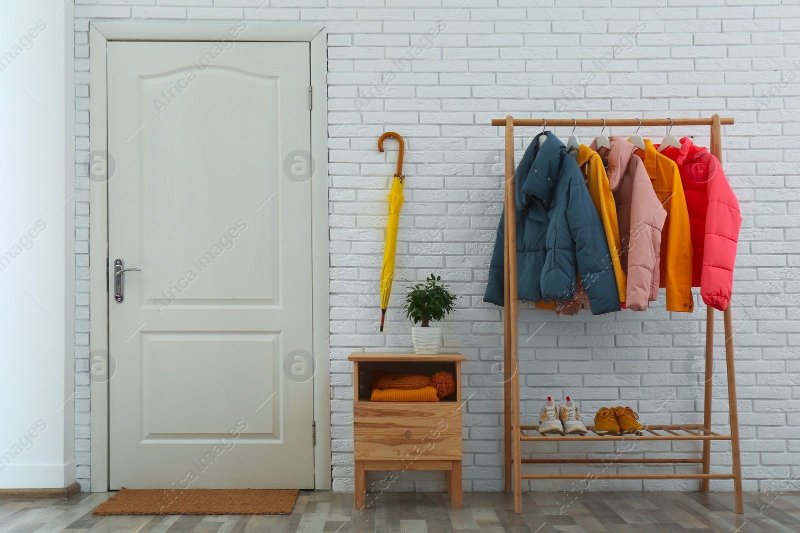 Photo of Wooden rack with stylish warm jackets in hallway