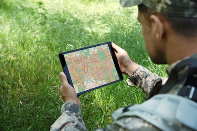 Soldier using tablet in forest, closeup view