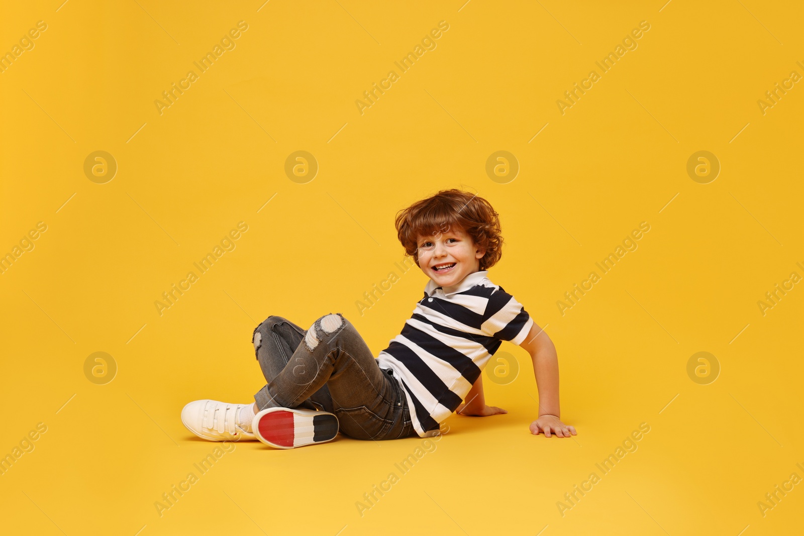 Photo of Happy little boy dancing on yellow background. Space for text