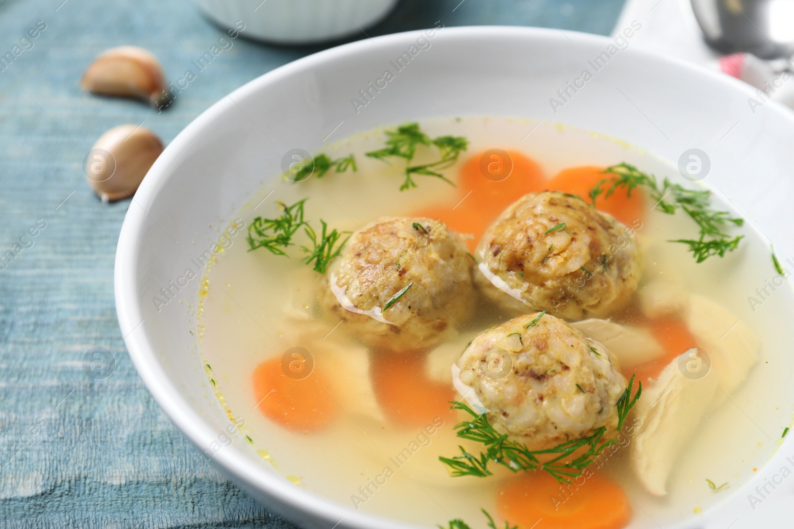 Photo of Bowl of Jewish matzoh balls soup on wooden table, closeup