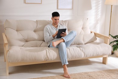Photo of Man using tablet on sofa at home