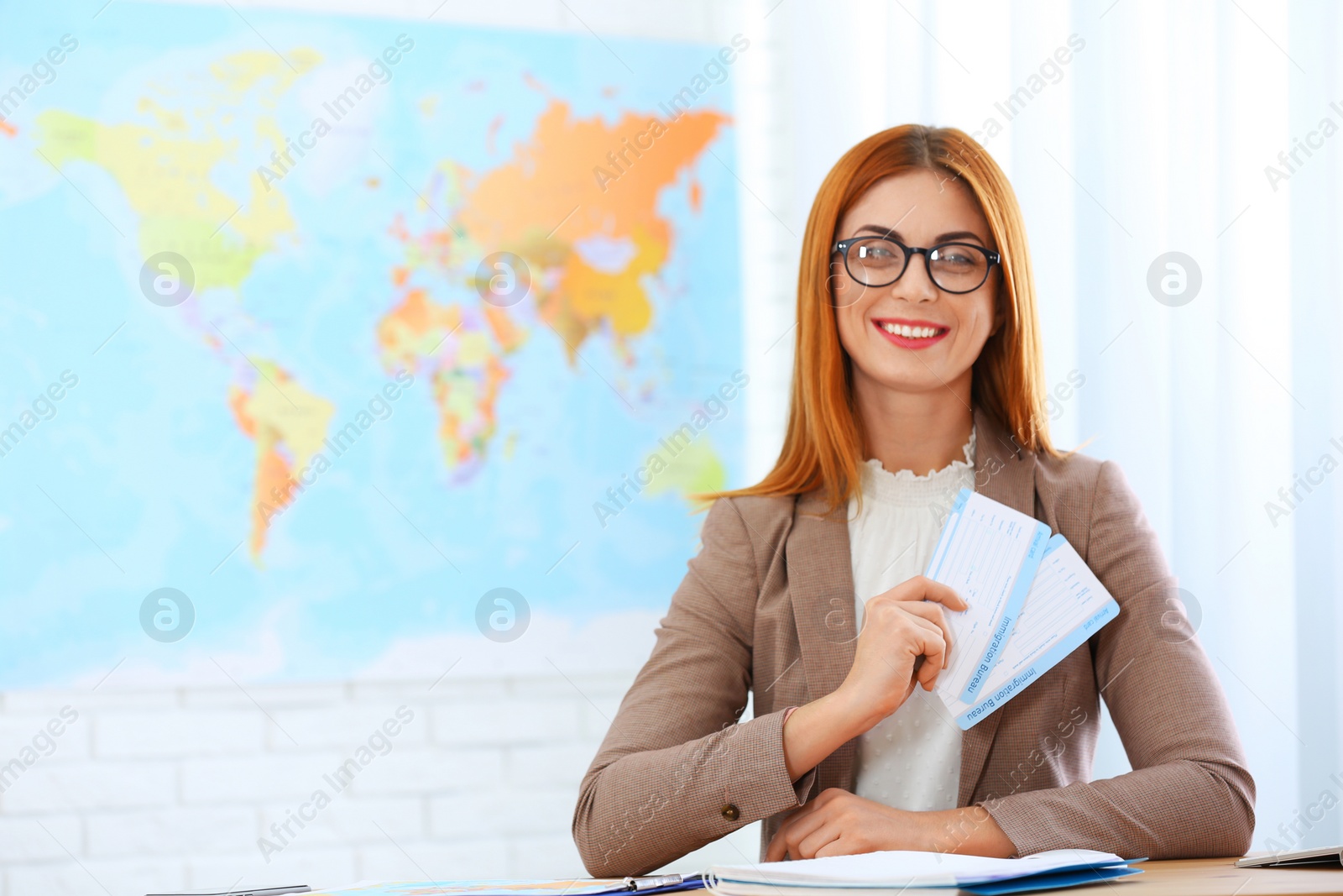 Photo of Beautiful consultant holding tickets in travel agency. Space for text