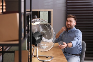 Man enjoying air flow from fan at workplace