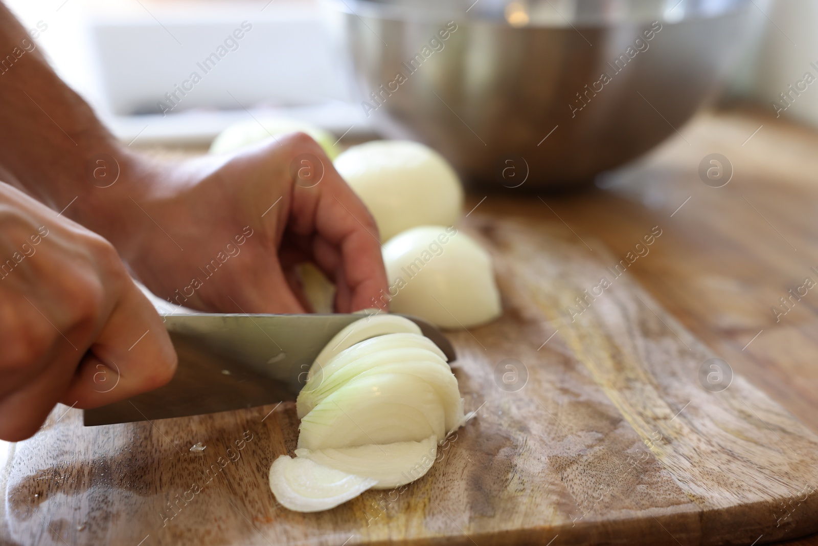 Photo of Woman cutting fresh ripe onion on wooden board, closeup. Space for text