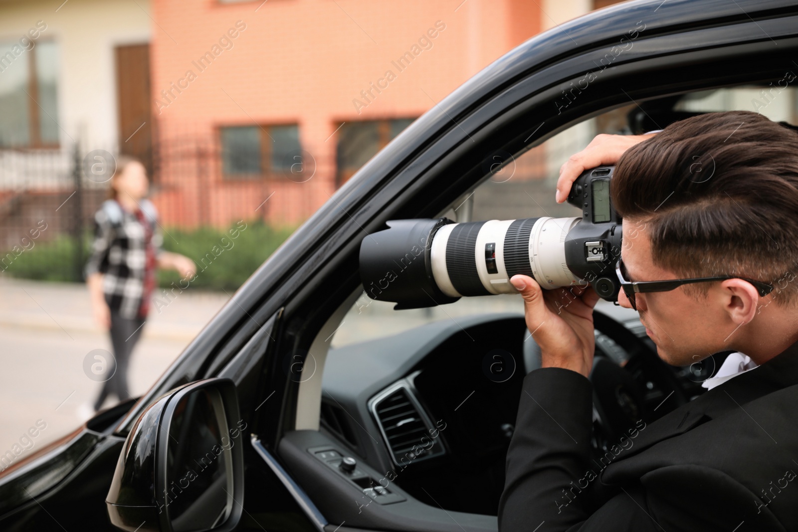 Photo of Private detective with camera spying from car